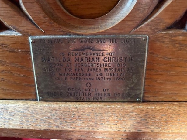 Photograph of a lectern with the inscription "To Serve The Word and The Light... In Remembrance of Matilda Marian Christie, born at Herbertshire, 1819, wife of the Rev. James Macfarlan of Muiravonside. She lived at Leslie Park from 1871 to 1890. Presented by their daughter Helen Douie, Nov. 15 1925."